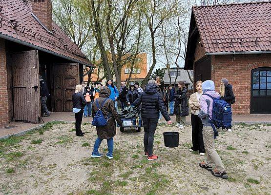 Grupa młodzieży przed budynkiem przygotowująca się do warsztatów terenowych.