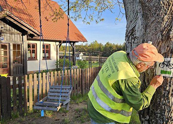 Wykonawca malujący oznczenie szlaku na drzewie.