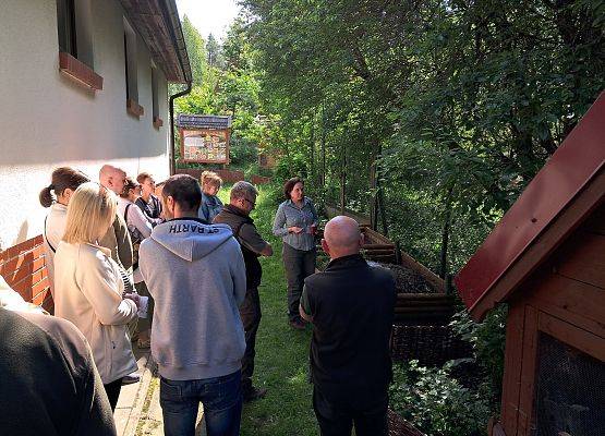 Grupa osób stojąca i oglądająca edukacyjne miejsce - komostownik w Zielonej Szkole w Schodnie.
