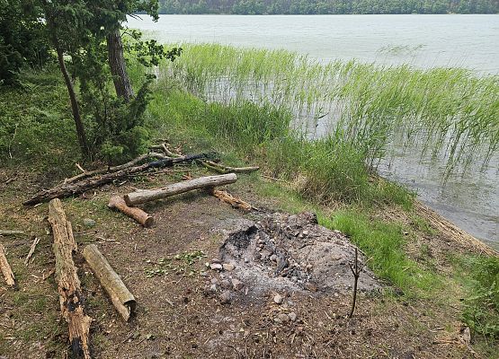 Ślady po wypalonym ognisku nad brzegiem jeziora.