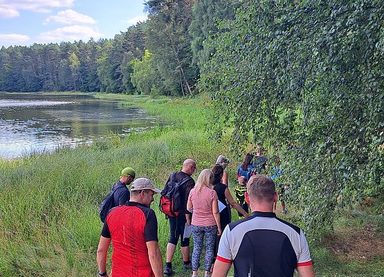 Idące osoby wzdłuż jeziora Schodno podczas warsztatów botanicznych.