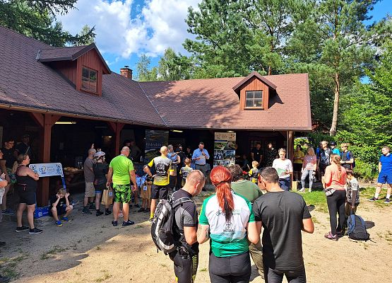 Na pieszym planie uczestnicy rajdu, w oddali wręczanie dyplomów przy wiacie.