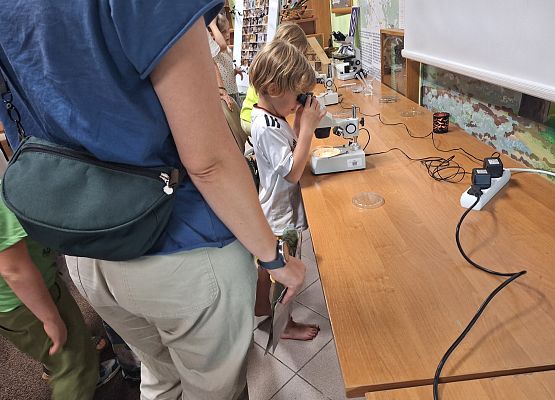 Młody uczestnik spotkania spogląda przez binokular