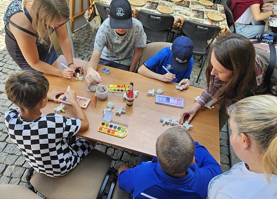 Przy stole dzieci malują modele gipsowe owadów